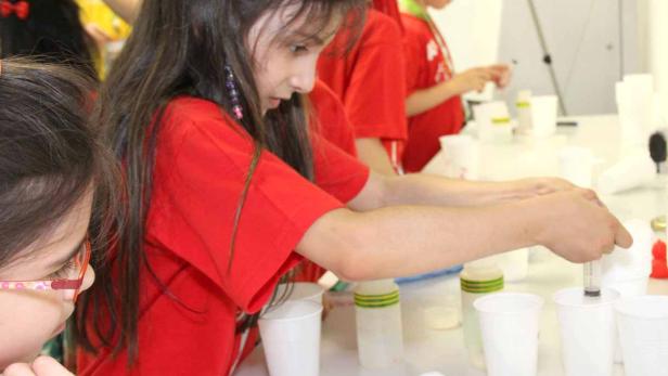 Mädchen experimentieren im Labor mit Pipetten und Bechern.