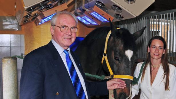 Ein Mann und eine Frau stehen neben einem Pferd unter einer Lichttherapieanlage.