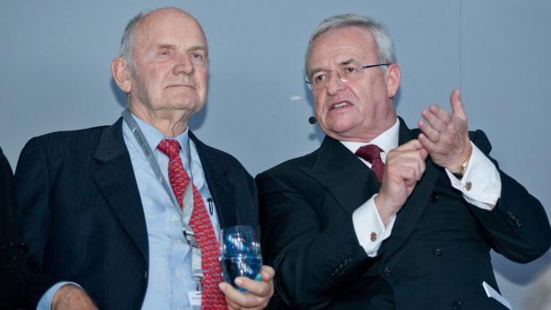 Zwei ältere Herren in Anzügen sitzen nebeneinander bei einer Veranstaltung.