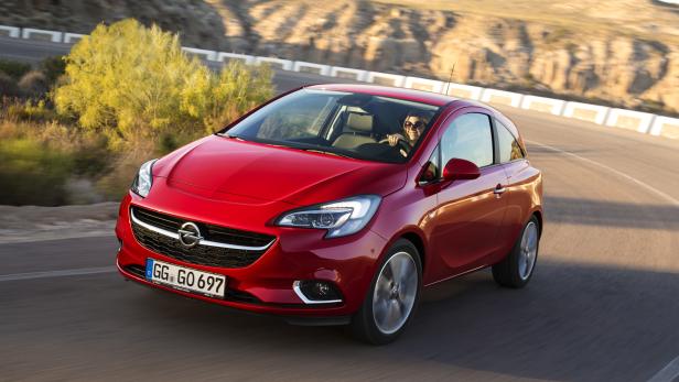 Ein roter Opel Corsa fährt auf einer kurvenreichen Straße.