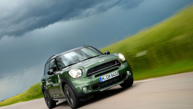 Ein grüner Mini Countryman fährt auf einer Landstraße.