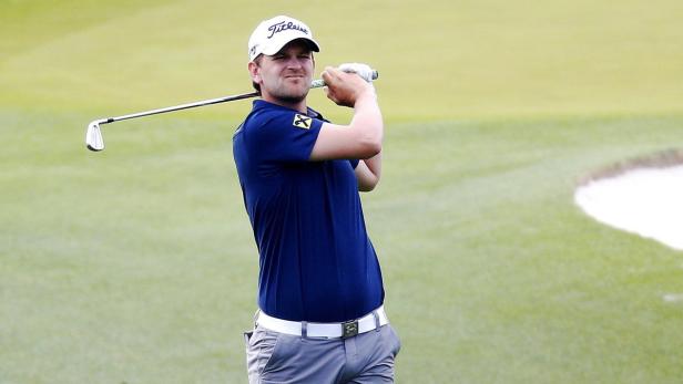 Ein Golfspieler schwingt seinen Schläger auf einem grünen Golfplatz.