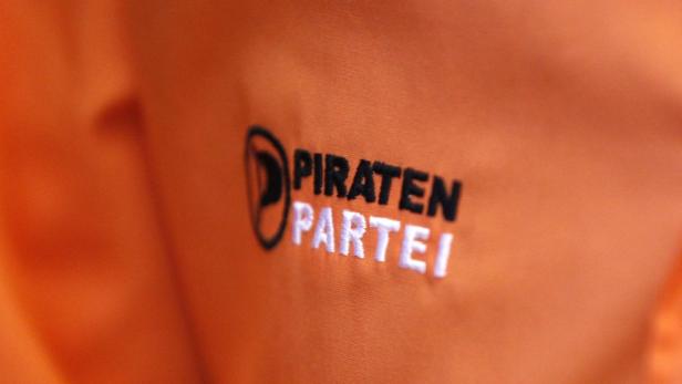 Das Logo der Piratenpartei auf einem orangefarbenen Stoffhintergrund.