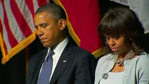 Barack und Michelle Obama bei einer Veranstaltung mit gesenkten Köpfen.