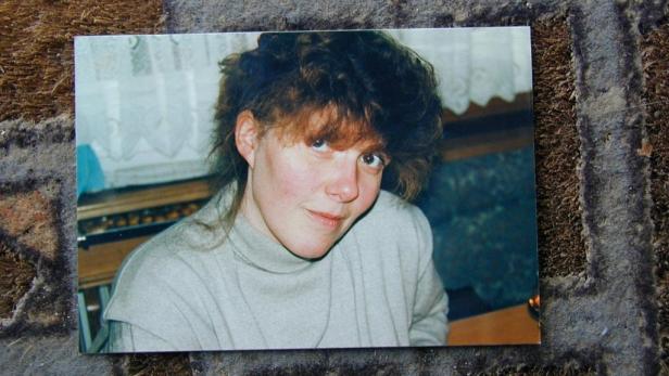 Porträt einer jungen Frau mit lockigem, braunem Haar und einem hellgrauen Rollkragenpullover.