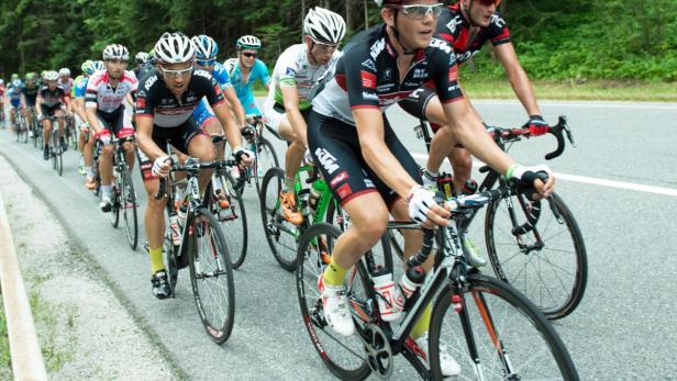 Eine Gruppe von Radfahrern fährt ein Rennen auf einer asphaltierten Straße.