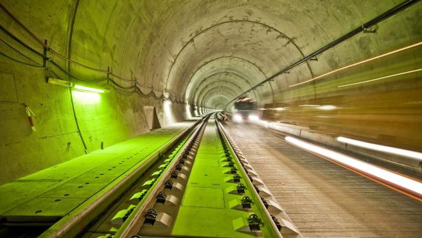 Ein Tunnel mit Bahngleisen und einem Fahrzeug mit Lichtstreifen im Hintergrund.