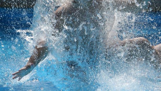 Ein Schwimmer erzeugt eine große Wasserfontäne im Schwimmbad.