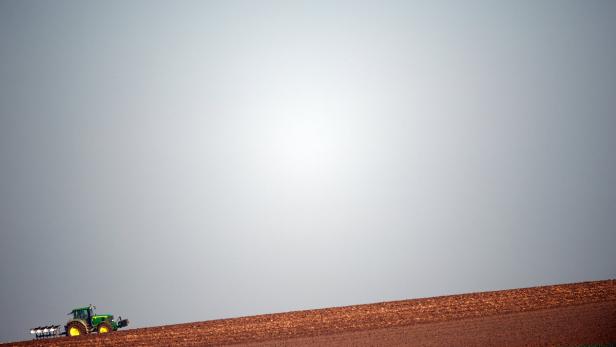 Ein Traktor pflügt ein Feld unter einem grauen Himmel.