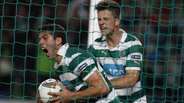 Zwei Fußballspieler in grün-weiß gestreiften Trikots jubeln hinter einem Netz.