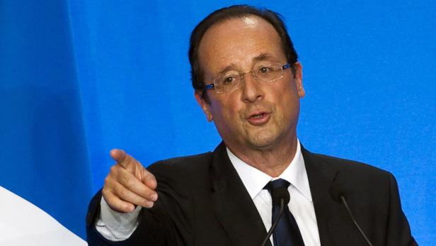François Hollande gestikuliert vor einem blauen Hintergrund.
