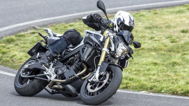 Ein Motorradfahrer fährt in voller Montur auf einer kurvigen Straße.