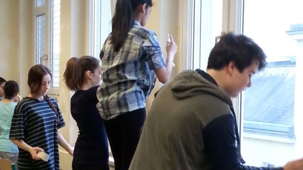 Eine Gruppe von Jugendlichen renoviert einen Raum und streicht Fensterrahmen.