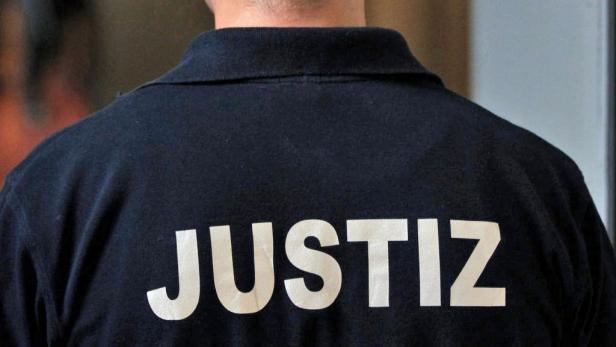 Auf dem Rücken eines Mannes steht in großen Buchstaben das Wort „Justiz“.