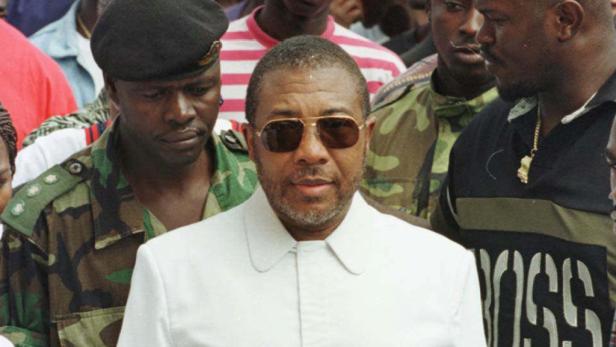 Charles Taylor, ehemaliger Präsident von Liberia, mit Sonnenbrille und weißem Anzug inmitten einer Menschenmenge.