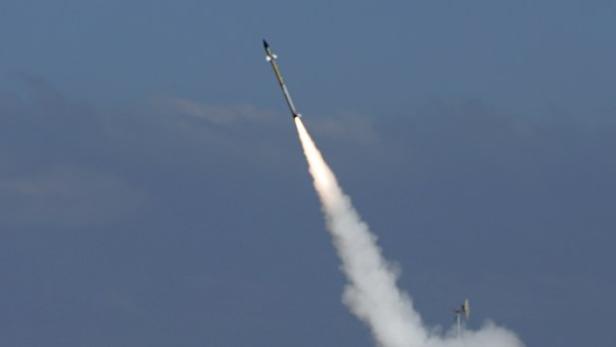 Eine Rakete startet mit einer Rauchwolke in den blauen Himmel.