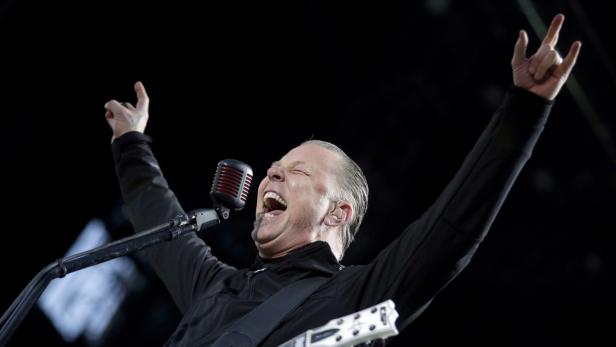 James Hetfield von Metallica singt mit erhobenen Händen auf einem Konzert.