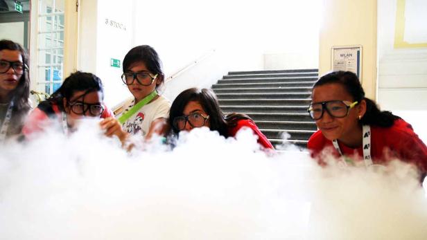 Eine Gruppe von Kindern mit Schutzbrillen experimentiert mit Trockeneis.