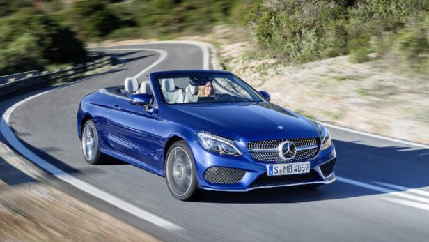 Ein blaues Mercedes-Benz C-Klasse Cabriolet fährt auf einer kurvenreichen Straße.