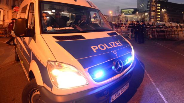 Ein Mannschaftswagen der Polizei mit eingeschaltetem Blaulicht steht auf der Straße.