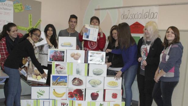 Eine Gruppe von Jugendlichen präsentiert eine Pyramide aus Lebensmittelbildern für ein Schulprojekt zum Thema Nachhaltigkeit.