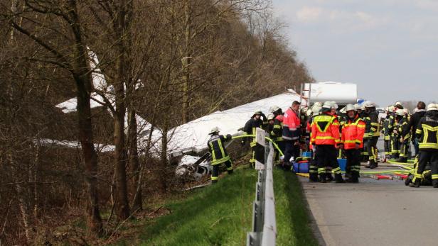 Feuerwehrleute arbeiten an der Absturzstelle eines kleinen Flugzeugs neben einer Straße.