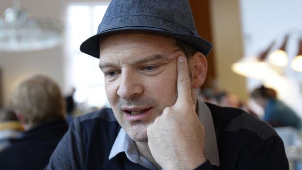 Ein Mann mit Hut denkt nach, den Finger an die Schläfe gelegt.