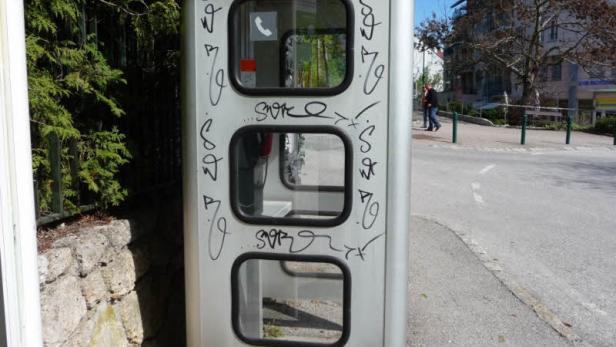 Eine Telefonzelle ist mit Graffiti beschmiert.