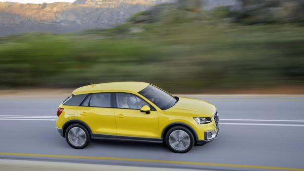 Ein gelber Audi Q2 fährt auf einer Landstraße.
