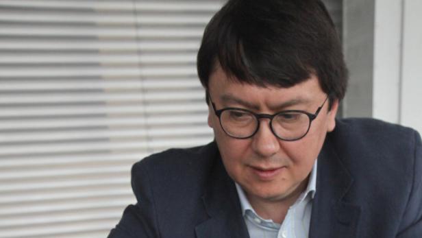 Ein Mann mit Brille und dunklem Haar schaut nach unten.