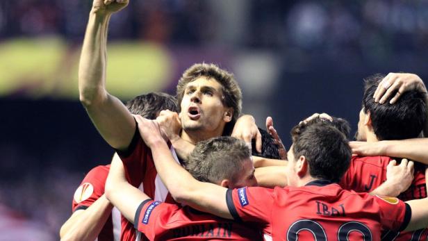 Eine Gruppe von Fußballspielern in roten Trikots feiert einen Sieg.