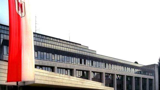 Eine rot-weiße Flagge weht vor einem modernen Bürogebäude.