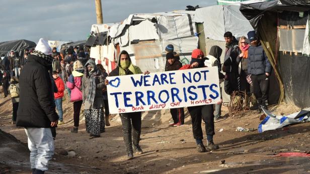 Menschen demonstrieren mit einem Schild „We are not terrorists“ in einem Lager.