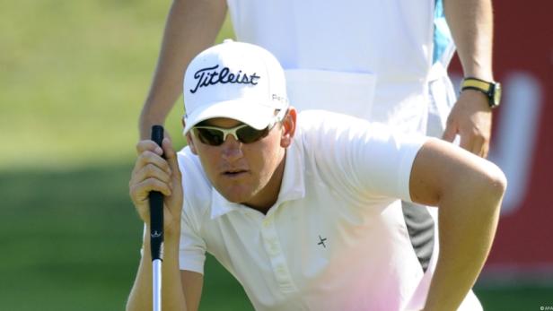 Ein Golfspieler mit Sonnenbrille und Kappe zielt mit seinem Schläger.