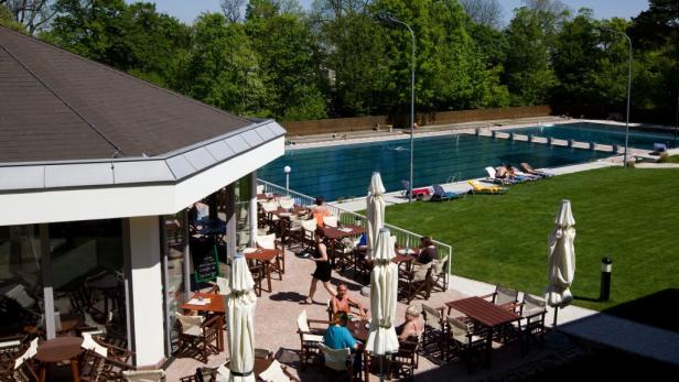 Ein Freibad mit Restaurant und Liegewiese an einem sonnigen Tag.