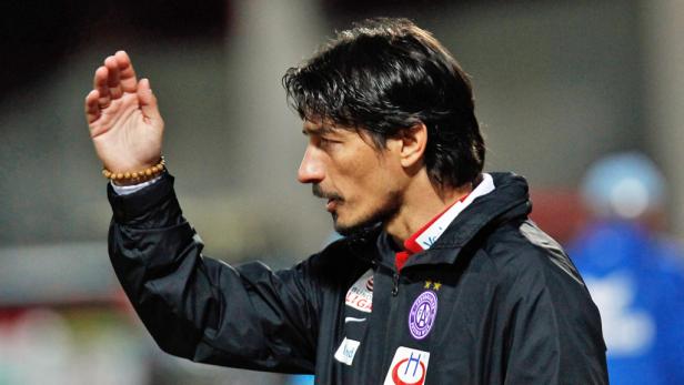 Ein Mann in einer schwarzen Jacke gestikuliert mit der Hand.