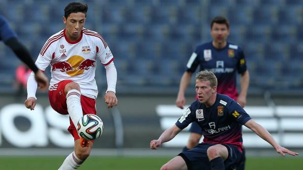 Ein Fußballspieler in einem weißen und roten Trikot dribbelt den Ball.