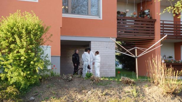 Mehrere Personen in Schutzanzügen stehen vor einem Wohnhaus.