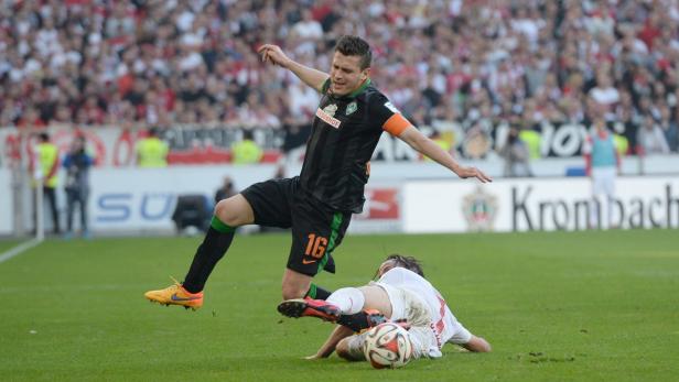 Ein Fußballspieler von Werder Bremen grätscht einen Gegenspieler ab.