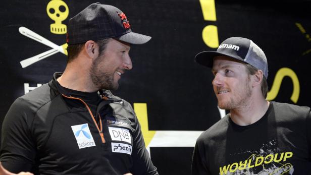 Zwei Männer mit Kappen stehen einander gegenüber und lächeln.