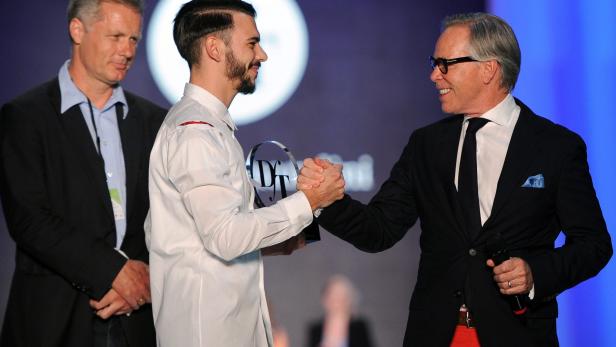 Zwei Männer schütteln sich die Hände, während ein dritter Mann daneben steht.