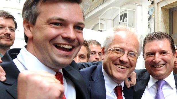 Eine Gruppe gut gelaunter Männer in Anzügen lächelt in die Kamera.