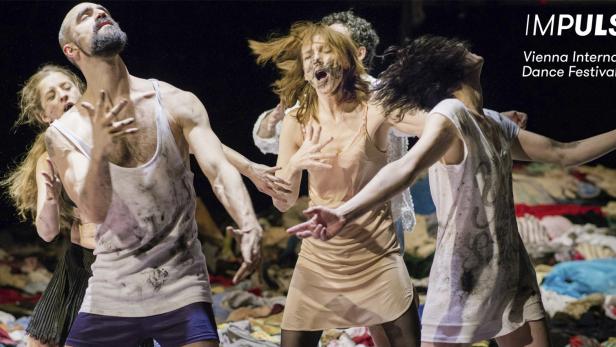 Mehrere Tänzer treten während des Vienna International Dance Festival auf einer Bühne voller Kleidung auf.