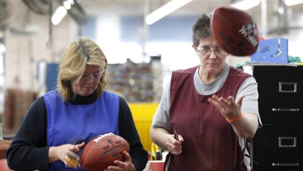 Zwei Frauen arbeiten in einer Fabrik an American Football Bällen.