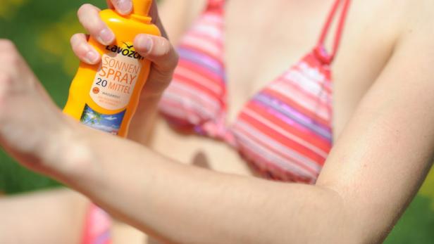 Eine Frau cremt sich mit Sonnenspray LSF 20 ein.