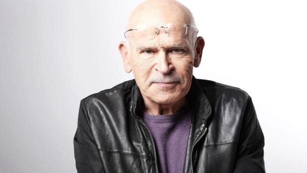 Ein Mann mit Glatze und Brille auf der Stirn trägt eine schwarze Lederjacke.