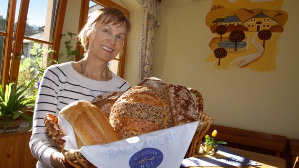 Eine lächelnde Frau hält einen Korb mit verschiedenen Brotsorten.
