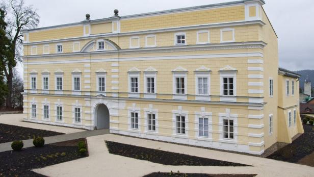 Ein gelbes, zweistöckiges Gebäude mit weißen Fensterrahmen und einem Torbogen.