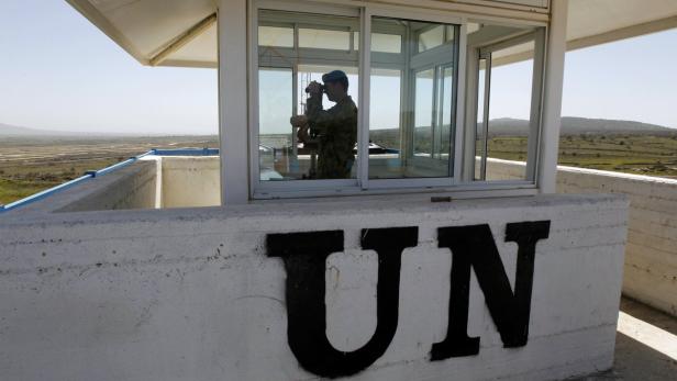 Australian Army Captain Scotty Morris of the unarmed United Nations Truce Supervision Organisation (UNTSO), who works with the U.N. Disengagement Observer Force (UNDOF), uses binoculars from an observation tower located on the Israeli side of the 1973 Golan Heights ceasefire line with Syria March 21, 2012. Blue-helmeted United Nations peacekeeping troops patrolling a slice of Syrian territory to maintain a ceasefire with Israel face new risks as violence between Syrian government loyalists and rebels gets closer. Picture taken March 21, 2012. REUTERS/Ronen Zvulun (POLITICS CONFLICT MILITARY)