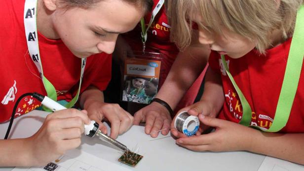 Zwei Kinder löten gemeinsam an einer elektronischen Schaltung.